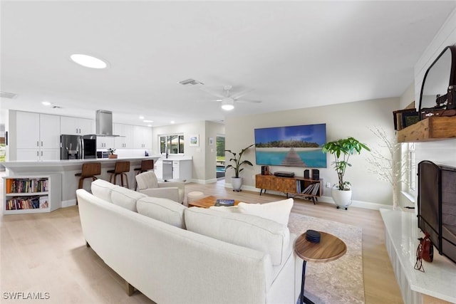 living room featuring a ceiling fan, recessed lighting, and light wood-style floors