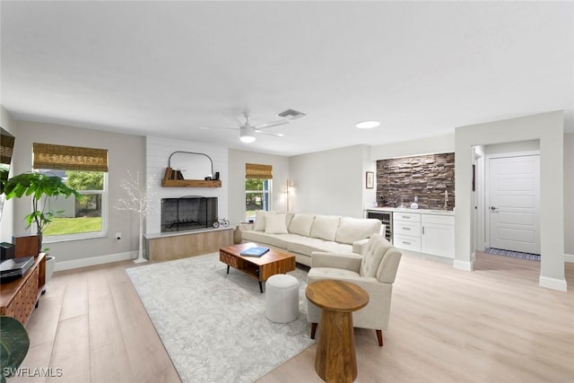 3795 Liberty Sq, Fort Myers, FL 33908 - living area featuring beverage cooler, bar with sink, a large fireplace, light wood-type flooring, and ceiling fan