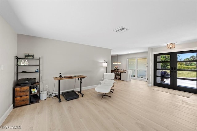 living area with baseboards, french doors, light wood-type flooring, and visible vents
