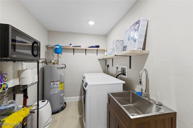 laundry area featuring a sink, light wood-style flooring, water heater, baseboards, and washing machine and dryer