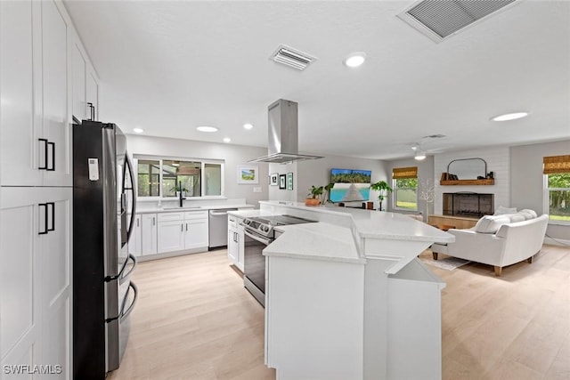 kitchen with island exhaust hood, white cabinetry, appliances with stainless steel finishes, and visible vents