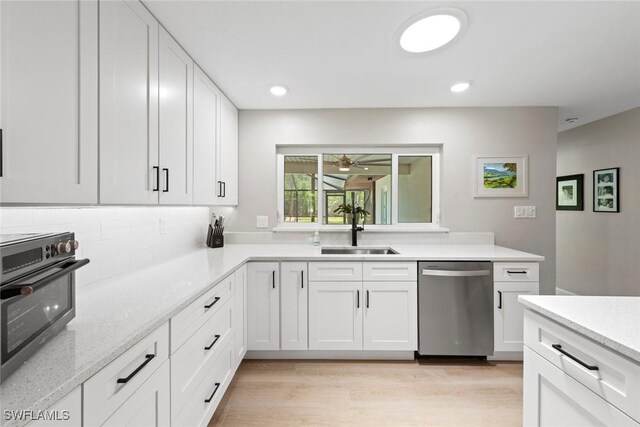 kitchen with a sink, stainless steel dishwasher, and white cabinetry