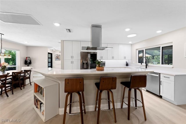 kitchen featuring island exhaust hood, white cabinetry, a kitchen island, and stainless steel appliances