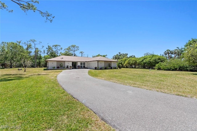 ranch-style home featuring a garage, driveway, and a front lawn