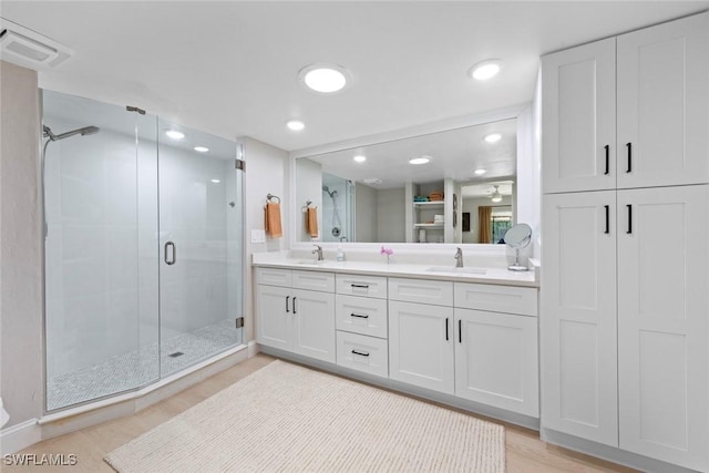 bathroom with double vanity, a sink, visible vents, and a shower stall