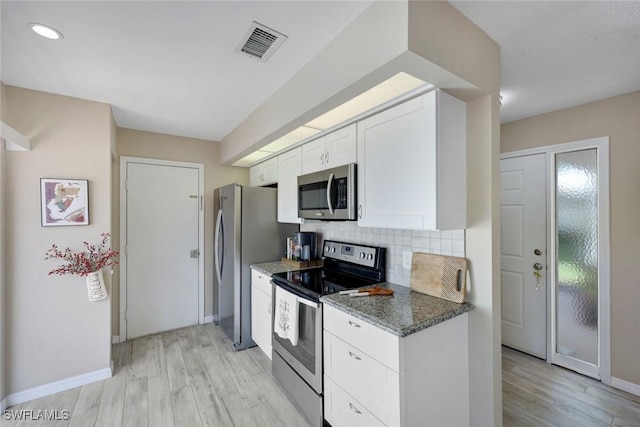 14871 Crescent Cove Dr, Fort Myers, FL 33908 - kitchen featuring appliances with stainless steel finishes, tasteful backsplash, white cabinetry, light wood-type flooring, and visible vents