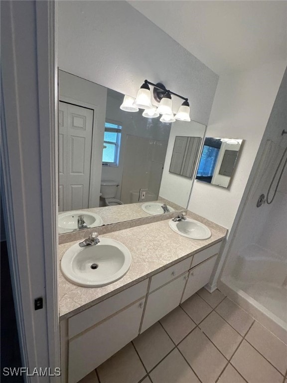 full bath with a sink, tile patterned floors, toilet, and a stall shower
