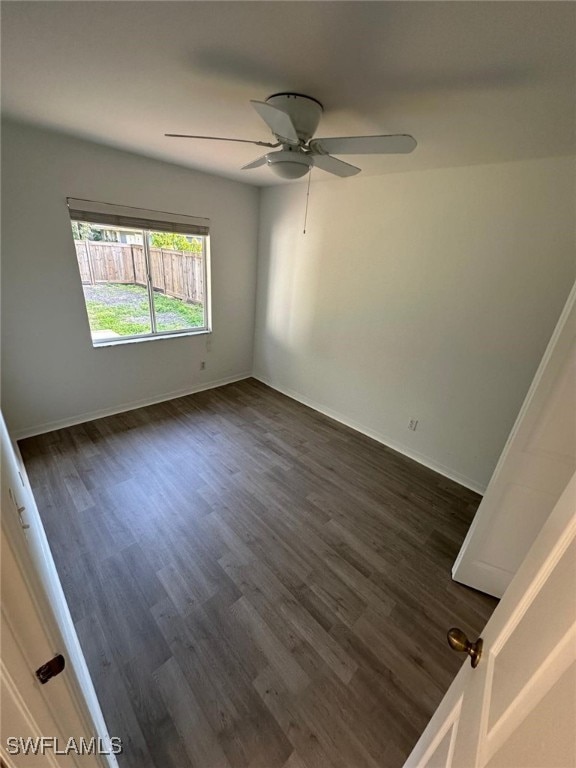 unfurnished room featuring baseboards, a ceiling fan, and dark wood-style floors