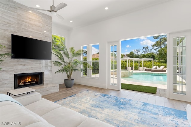 living area with a ceiling fan, wood finished floors, recessed lighting, a fireplace, and baseboards