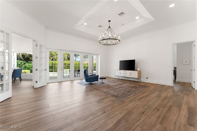 unfurnished living room featuring french doors, a tray ceiling, healthy amount of natural light, recessed lighting, and crown molding