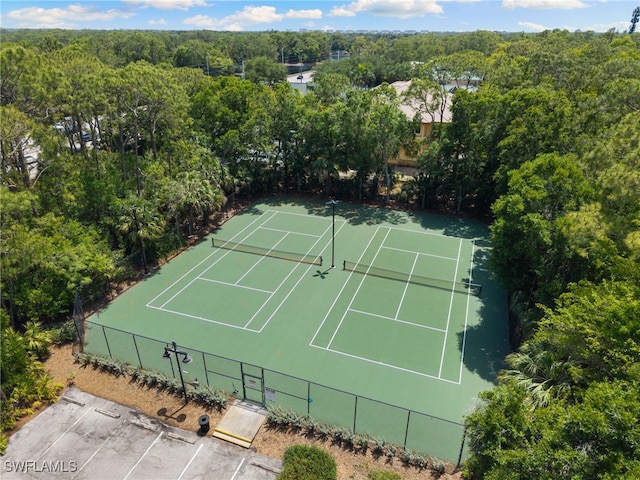 view of tennis court featuring fence and a forest view