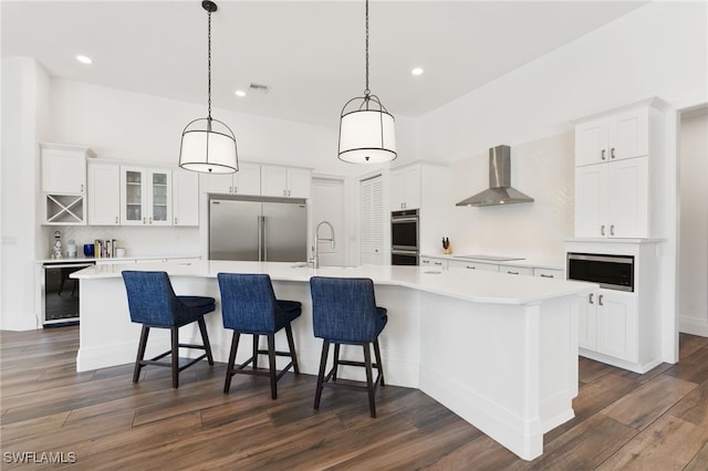 kitchen with wall chimney exhaust hood, stainless steel appliances, beverage cooler, white cabinets, and recessed lighting