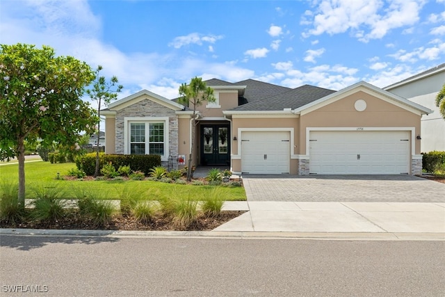 17716 Corkwood Bend Trl, Punta Gorda, FL 33982 - view of front of property with stone siding, french doors, stucco siding, and an attached garage