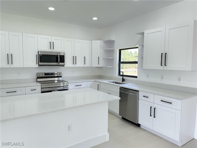 kitchen with stainless steel appliances, open shelves, white cabinets, and a sink
