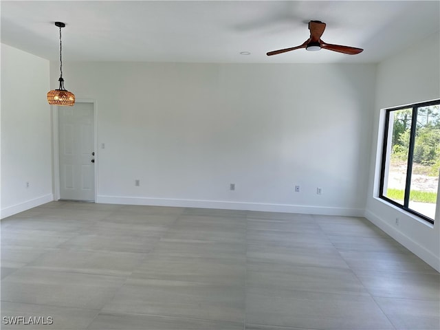 unfurnished room featuring a ceiling fan and baseboards
