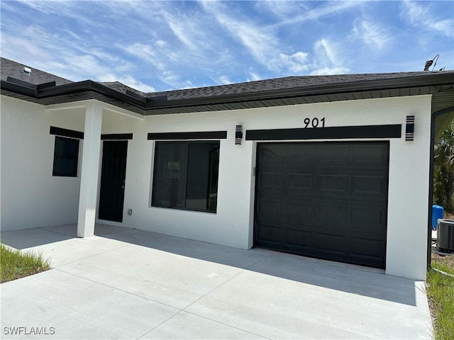 view of exterior entry with driveway, central AC unit, stucco siding, and a garage