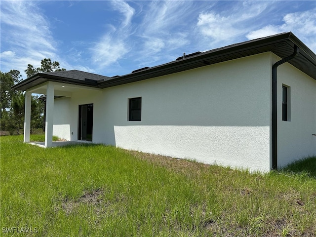 exterior space with stucco siding and a yard