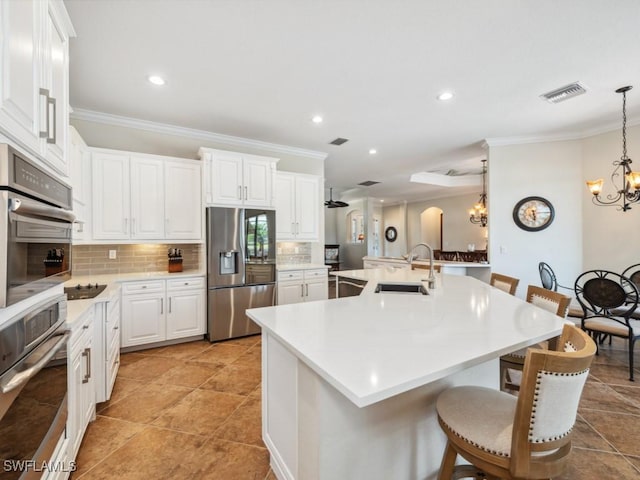 kitchen featuring a sink, decorative backsplash, a notable chandelier, visible vents, and appliances with stainless steel finishes