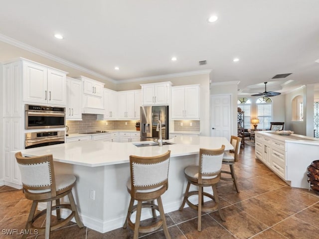 kitchen featuring tasteful backsplash, a sink, appliances with stainless steel finishes, a spacious island, and a ceiling fan
