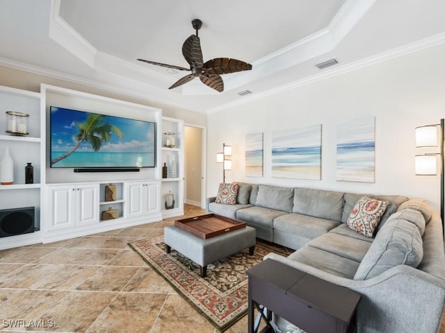 living area with crown molding, a tray ceiling, a ceiling fan, and built in shelves