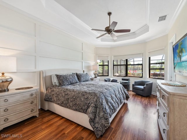bedroom featuring visible vents, a tray ceiling, ornamental molding, and dark wood finished floors