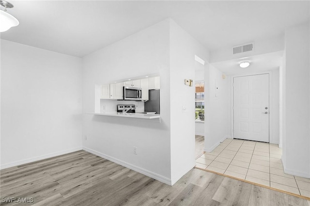 5731 Foxlake Dr Unit 1, North Fort Myers, FL 33917 - kitchen featuring visible vents, light wood-style flooring, light countertops, white cabinets, and appliances with stainless steel finishes