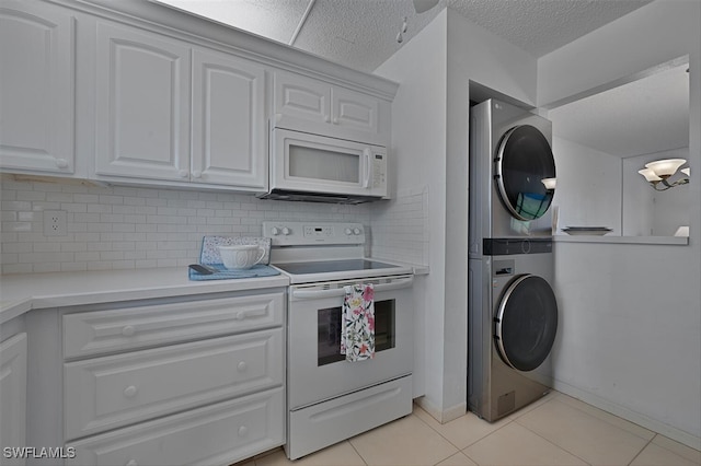 kitchen featuring stacked washer and clothes dryer, white cabinetry, white appliances, light countertops, and tasteful backsplash
