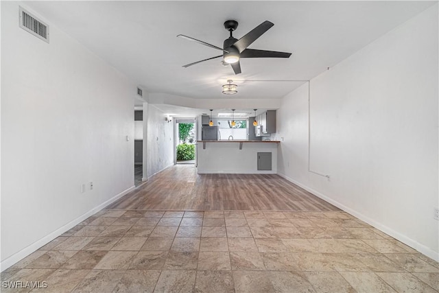 unfurnished living room with baseboards, ceiling fan, and stone finish flooring
