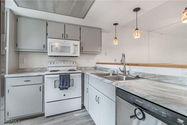 kitchen featuring white appliances, a sink, gray cabinetry, light wood-style flooring, and light countertops