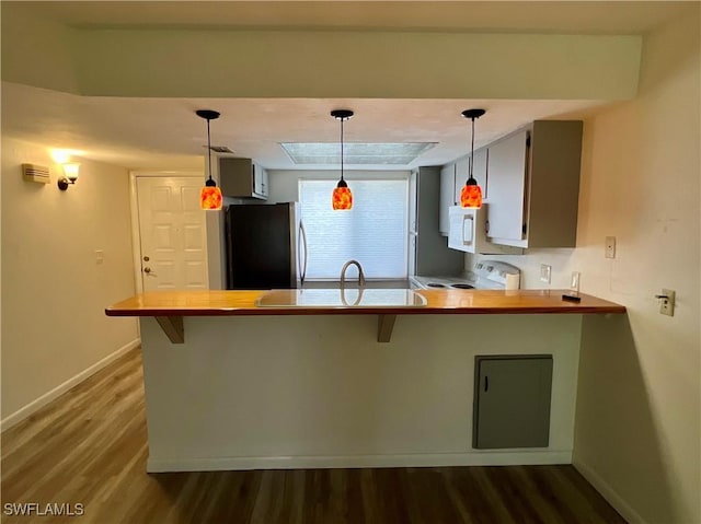 2241 E 5th St Unit 103, Lehigh Acres, FL 33936 - kitchen with freestanding refrigerator, dark wood-style flooring, baseboards, a peninsula, and a breakfast bar area