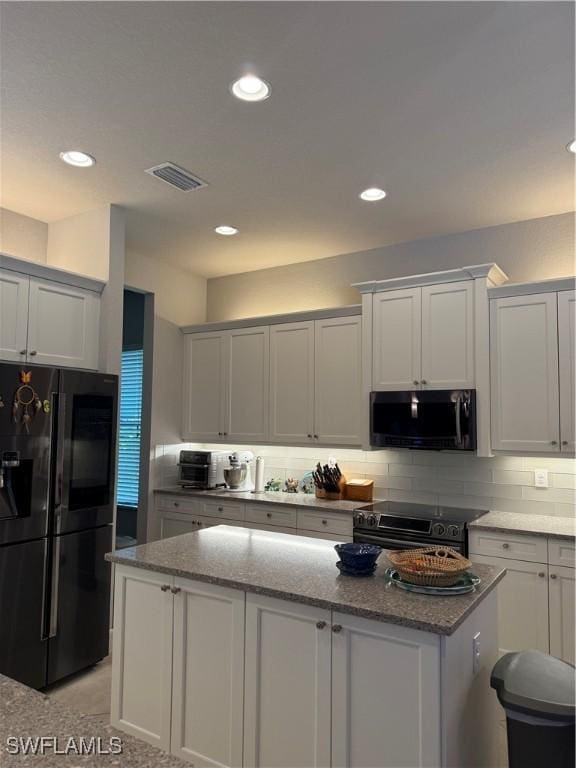 kitchen featuring visible vents, black fridge, tasteful backsplash, and electric range oven