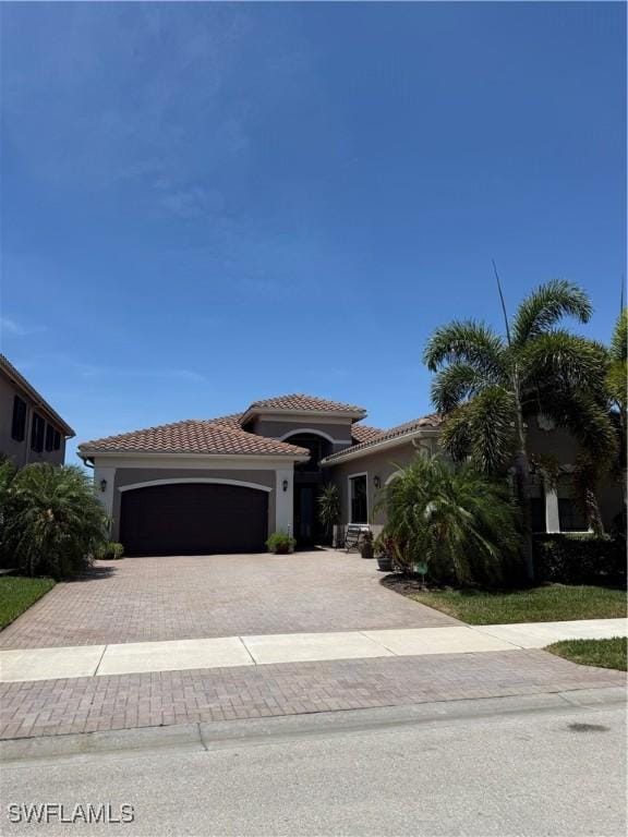 mediterranean / spanish home with decorative driveway, a garage, a tile roof, and stucco siding