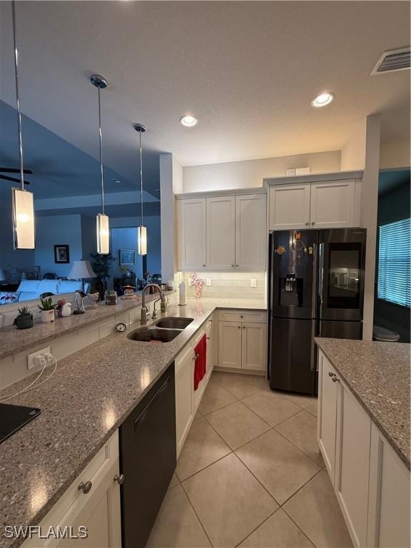 kitchen with visible vents, a sink, black appliances, dark stone countertops, and open floor plan
