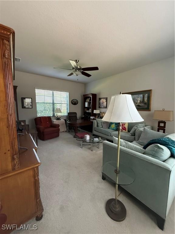 carpeted living room featuring a ceiling fan and visible vents