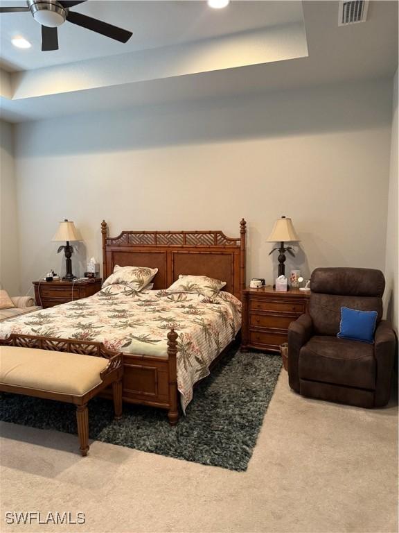 carpeted bedroom featuring visible vents, a ceiling fan, a tray ceiling, and recessed lighting