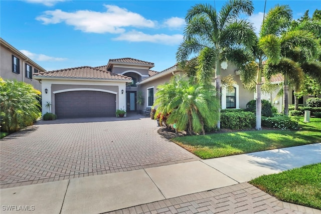 11692 Stonecreek Cir, Fort Myers, FL 33913 - mediterranean / spanish-style home featuring stucco siding, decorative driveway, an attached garage, a front lawn, and a tile roof