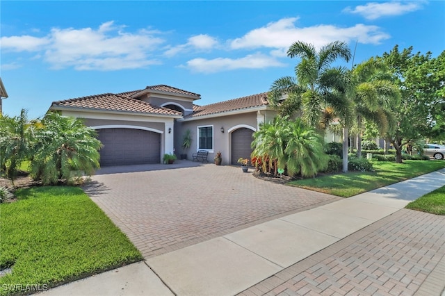 11692 Stonecreek Cir, Fort Myers, FL 33913 - mediterranean / spanish home with an attached garage, stucco siding, decorative driveway, a front lawn, and a tile roof
