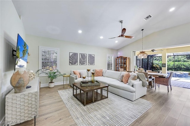 living area featuring visible vents, ceiling fan, lofted ceiling, and light wood finished floors