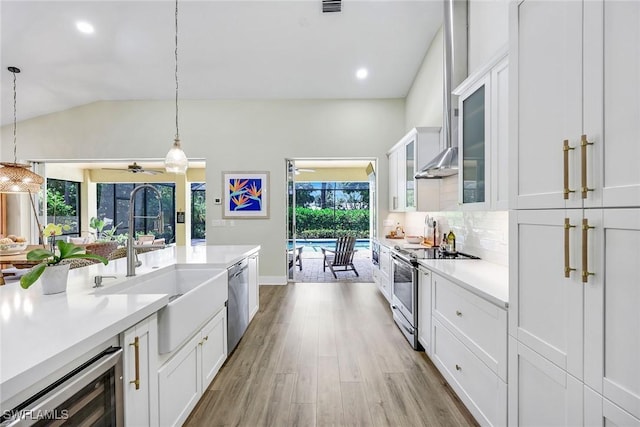 kitchen featuring white cabinets, a sink, appliances with stainless steel finishes, light wood-type flooring, and a ceiling fan