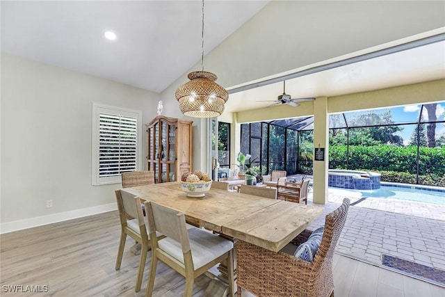 dining space with a sunroom, high vaulted ceiling, light wood-type flooring, a ceiling fan, and baseboards