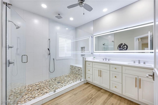 full bath featuring a ceiling fan, a sink, a shower stall, and wood finished floors