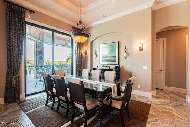 dining space featuring visible vents, arched walkways, baseboards, a raised ceiling, and ornamental molding