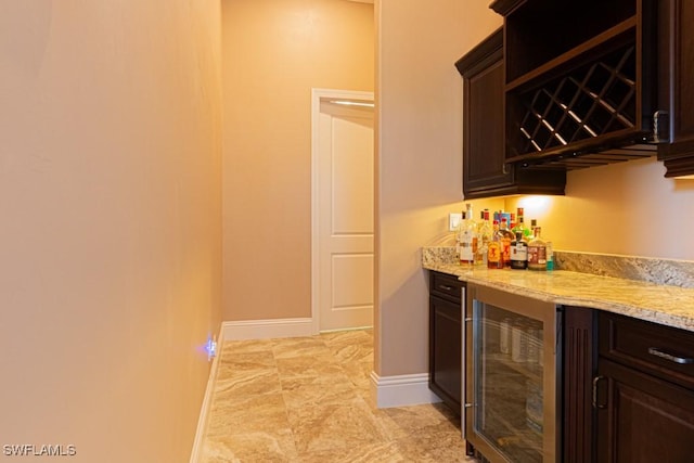 bar with beverage cooler, a dry bar, and baseboards