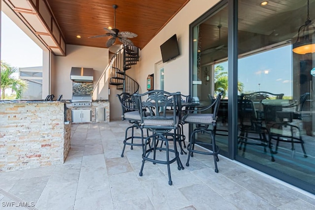 view of patio / terrace with stairs, outdoor wet bar, exterior kitchen, a ceiling fan, and a grill