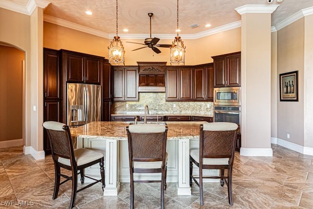 kitchen featuring appliances with stainless steel finishes, ceiling fan, light stone countertops, and a kitchen breakfast bar