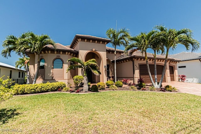 mediterranean / spanish home with driveway, a tile roof, a front lawn, an attached garage, and stucco siding