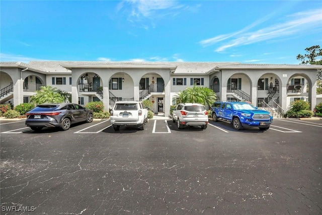 view of property featuring stairs and uncovered parking