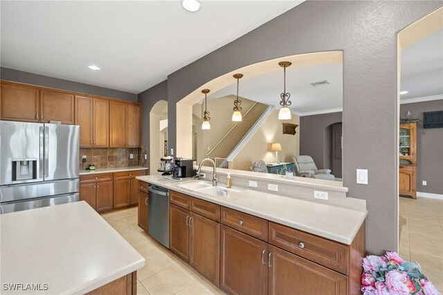 kitchen featuring decorative backsplash, a sink, arched walkways, appliances with stainless steel finishes, and light tile patterned floors