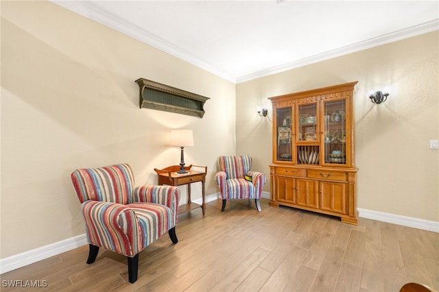 sitting room featuring light wood-style floors, baseboards, and crown molding