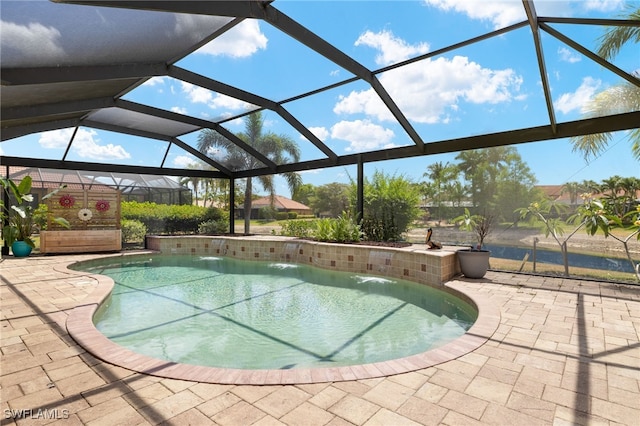 outdoor pool featuring glass enclosure and a patio area